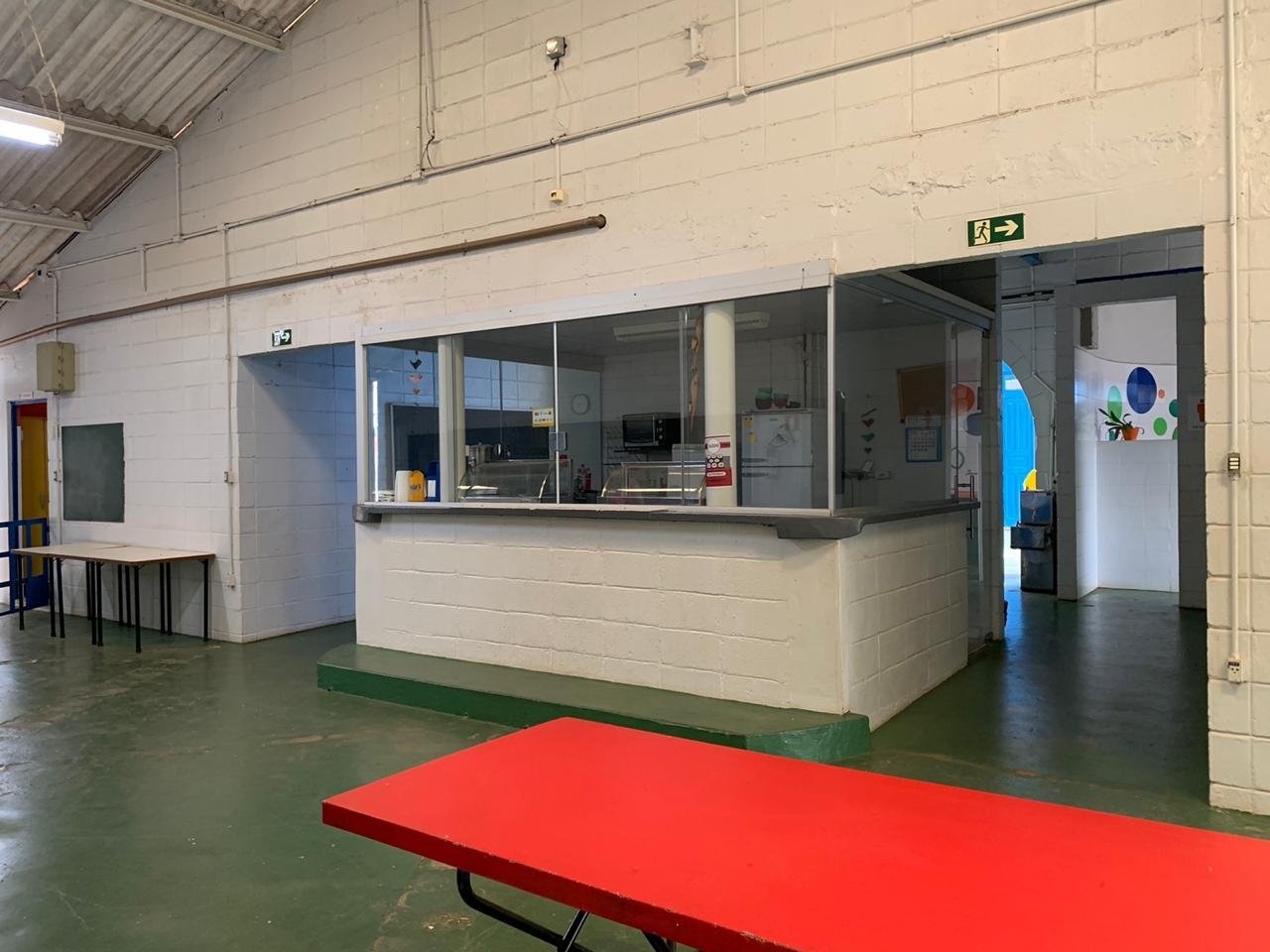 Pátio coberto da Escola Coopep com mesas e cantina