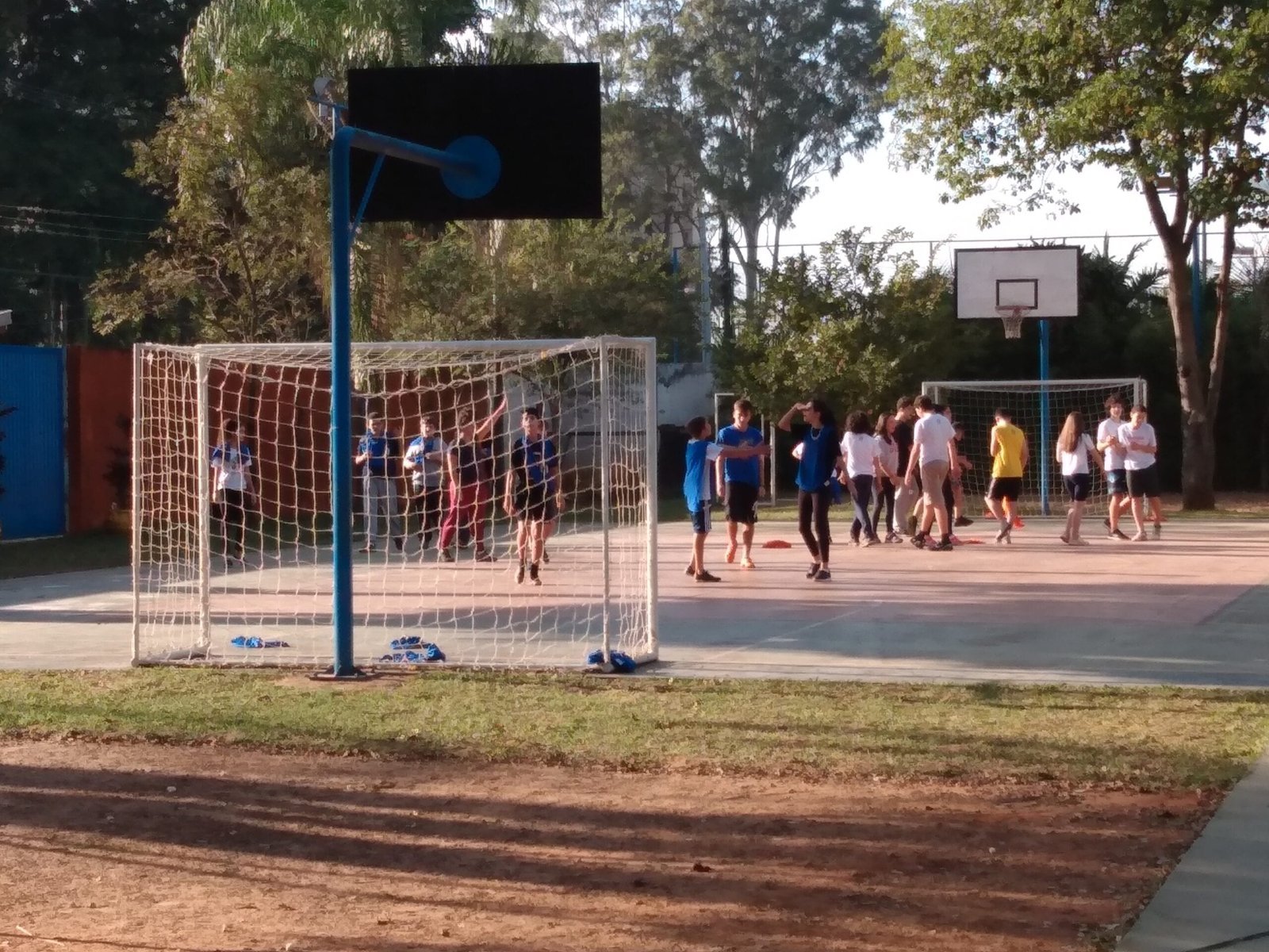 Quadra poliesportiva e campo da Escola Coopep com o prédio azul ao fundo